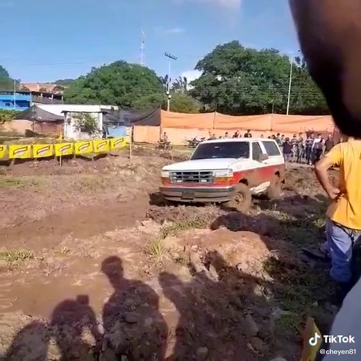 Red and White SUV Struggles Through Muddy Terrain