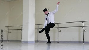 A macho man dances in a tie and a white shirt, a cheerful and positive guy, an elegant man in a hat creatively dances a street dance.