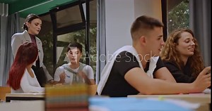 High school students collaborate on a project during class with the help of their teacher. They work together, share ideas, and learn from each other in a supportive environment.