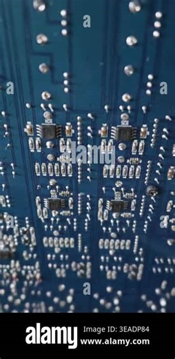 A close-up macro view reveals the intricate details of a blue printed circuit board filled with electronic components. Shiny solder joints and integrated microchips line the hardware Stock Video Footage - Alamy