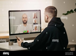 Remote work. A back view of a man during a video call with his colleagues on the desktop computer Stock Photo - Alamy