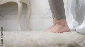 Close up shot of the woman's first morning step from the bed to the carpet floor with bared feet in her bedroom, getting up from the bed, very beginning of the day, FullHD high quality, 4k prores