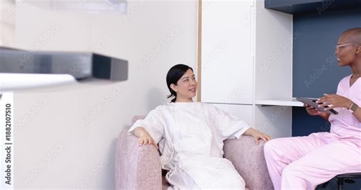 Diverse women patient and nurse talking in clinic after asking, nurse using tablet showing results