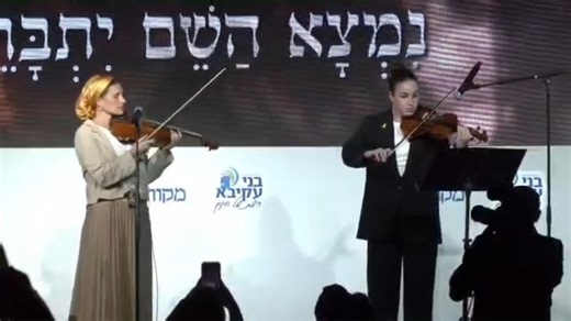 Hamas captivity survivor Agam Berger performed a moving duet with Rachel Goldberg, recently-remarried widow of Rabbi Avi Goldberg, who fell in battle in southern Lebanon last year. The two women performed "Afilu B'Hastara," a song about faith, and the "Berditchever Melody" at the International Conference Center in Jerusalem during the National Education Conference hosted by the Bnei Akiva Yeshivot and Ulpanot Center and Makor Rishon. | Arutz Sheva - Israel National News