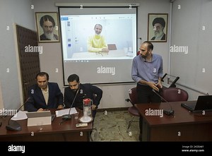 Majid Nouri (R), son of the former staff member of the Iranian judiciary, Hamid Nouri, looks at two men while standing under a portrait of Iran’s Supreme Leader Ayatollah Ali Khamenei (Top R), his father Hamid Nouri (C), and Iran’s Late Leader Ayatollah Ruhollah Khomeini during a video conference session for analyzing of the bill of Hamid Nouri’s family to the Swedish court in the Faculty of Economics of the Allameh Tabataba'i University in downtown Tehran on July 8, 2022. In November 2019, Hami
