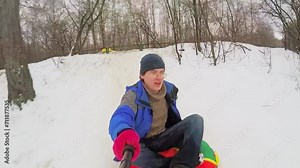 Man in colorful clothes sits on top of an inner tube and rides