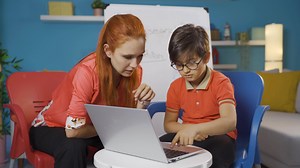 The teacher is teaching her student how to use a laptop.