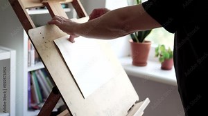 Man installing an easel for painting. Artist preparing his work space.