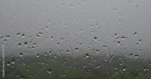 A photo of raindrops of various sizes on a window, taken from inside. zoom in