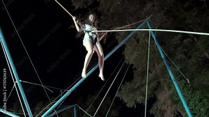 Girl playing bungee jumping trampoline outside at night