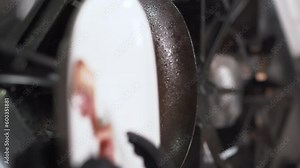 Cook hands take the fried golden bacon from the pan putting it on a plate. Process of cooking in a restaurant concept