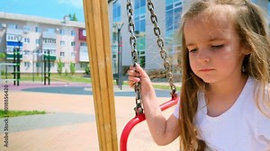 child rides on swing in the park. happy family kid dream concept. child girl swings on a swing at the playground. kid lifestyle playing on swing outdoors