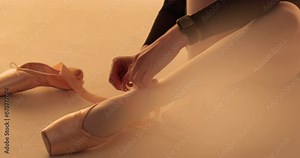 Ballerina putting on tying classic pointe shoes for dance lessons. Ballerina puts on pointe shoes in dance class. Classical ballet dancer woman in dance studio. Ballet school concept