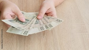 Close-up of female hands holding Polish złoty banknotes, illustrating themes of finance, international trade, and currency exchange