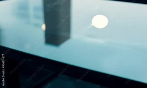 A reflective glass table surface with soft lighting and blurred background elements.