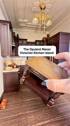 This Victorian kitchen island has a twist because I’m not typically a matchy matchy person. 😃 While renovating this moody, Victorian kitchen in my dollhouse renovation, I couldn’t decide if the island should match the marble counters or become a bold copper statement piece… so I made both. From an unfinished table to two completely different island tops, this miniature Victorian kitchen now has options. Deep raisin cabinets, brass hardware, layered chandelier lighting, and rich architectural de