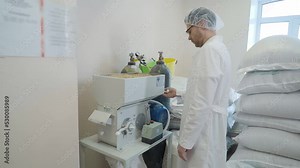 Operating the machine for grain ingredient processing at the alcohol brewery. Brewery machine grinds the barley grains. Machine refining the grain used for beer manufacturing at the brewery.