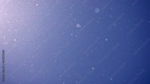 Pollen and dust flying in the air like snowflakes against blue sky background. Super slow motion shot. Natural light and texture.