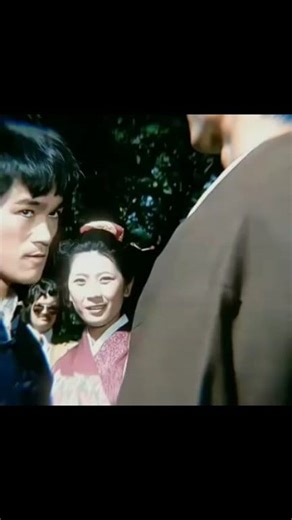 In this iconic scene from The Dragon, Bruce Lee, the legendary martial artist, showcases his extraordinary Kung Fu skills. Standing at the gate, he faces off against an opponent in a tense cultural showdown. His fast and precise movements highlight his visual power and incredible body control. The shot captures a mix of tension and focus, reflecting Bruce Lee’s spirit of martial arts and challenge. His smooth and complex techniques mirror his fighting philosophy, making him a timeless icon in th
