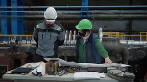 Turbine manufacturing factory. Heavy industry. Despite the new coronavirus the inspection took the place at the factory. The worker on the left watched the inspector making the correction marks.