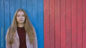 Girl on colourful wooden eco background. Dreamy mood. Girl is standing on colored background and wathes into the camera. The right side of background is free.
