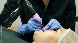 Micro pigmentation of lips process. Female permanent make up master holding machine applying pigment of woman client lips. Beauty and aesthetic treatment concept