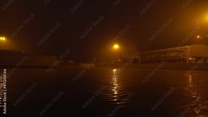 Building site on a riverside seen from a boat in the night with orange street lights