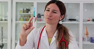 Female doctor carefully looks at syringe, make up correct dosage