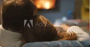 A happy young couple hugging and cuddling on the couch in front of a fireplace