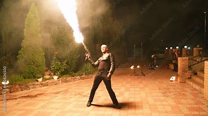 Fire performance show. Male artist performing with Flamethrower open air on the festival night. Fire dancer making show with flame outdoor at venue for tourists. Man working with fire on the street.
