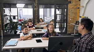 Teacher of high school something explaining and showing for students on laptop computer in information technology class