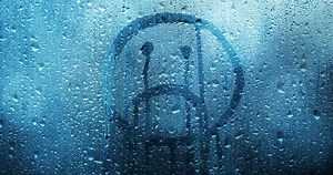 Sad upside down smiley on a rainy window background.