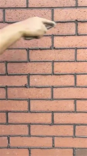 A worker applying mortar between bricks using bag