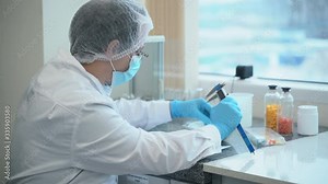 Man employee measures pills and writes report at table in pharmaceutical company spbas. Male specialist testing tablets, holding instrument in hands, then taking notes at desk in laboratory. Scientist