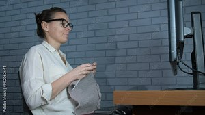 Female knitting against computer. A woman knitting against computer screen. A concept of learning something online.