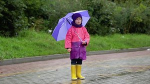 Child with an umbrella walks in the rain. Happy boy with umbrella outdoors