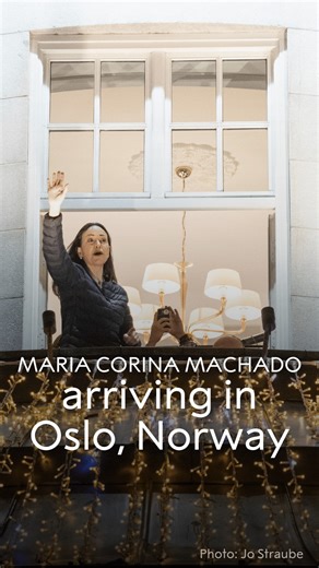 One week ago, 2025 Nobel Peace Prize laureate Maria Corina Machado arrived in Oslo, Norway. From the window of the Grand Hotel, she waved to a crowd singing in the street below. Moments later, she appeared on the street — climbing over barriers to embrace supporters who had gathered to welcome her. Machado had missed the award ceremony by a few hours. Her journey to Oslo required a secret departure from Venezuela, undertaken in defiance of a travel ban and after more than a year in hiding. | Nob