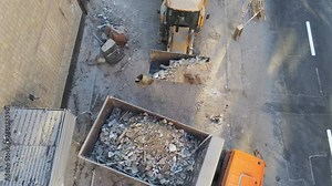 Bulldozer loader uploading waste and debris into dump truck at construction site near road. building dismantling and construction waste disposal service. Aerial drone industrial background. Stock Video