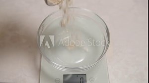 flour is poured into a bowl placed on kitchen scales, carefully measuring the exact amount of flour needed for a baking recipe, homemade cooking, measuring ingredients precisely