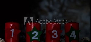 Four Advent red candles with numbers burning, fir branches and Christmas zero waste decorations in dark room in evening. Holiday preparation. Catholic traditions of Christmas new year winter holidays