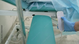 Using the remote control, the nurse raises the couch. The nurse raises the patient's couch using the remote control.