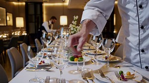 Chef arranging glassware and cutlery on an elegant table setting in a luxury restaurant, preparing for a special event or fine dining experience, with another waiter working in the background | Premium Stock Video Footage