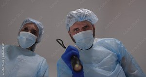 Doctor and nurse bent over the patient. He touch the pulse examines the patient, shines a flashlight in the eyes and checks reaction of pupils, pronounced death and covered face with a sheet.