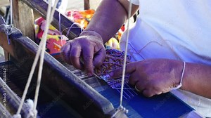 Close-up of hands weaving the tapestry with diverse bright threads on a classic Asian loom at work. Traditional hand weaving of the mountain tribes of northern Thailand.