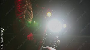 Young bearded man in leather jacket stands near his motorcycle in night parking and turns on headlights. Slow motion. Riding motorcycle gives sense of freedom and adventure. Extreme sports concept Stock Video