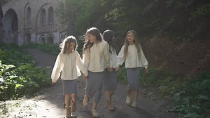 Girls in traditional clothes are walking near ancient castle. Concept of learning history.