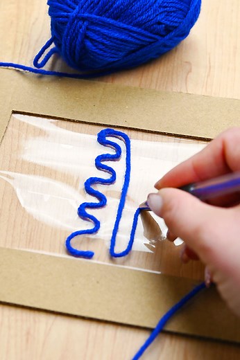 🧶✏️ A pen with no ink? Still iconic. This yarn pen art hack is the coolest way to create designs—no paint, no mess, just yarn and tape and total creativity. 😍👏 https://onelittleproject.com/yarn-pen-painting-hack/ | One Little Project