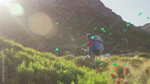 Male hiker pausing and checking map while ascending hiking trail, green triangles overlaying path