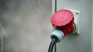 Raindrops are seen on industrial electric plug during heavy rain