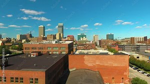 Low to high aerial reveal of the built up city of Omaha, high-rises scattered along the skyline on a bright sunny day.